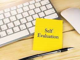 An image showing and pen, keyboard and a Post-it note with "self evaluation" written on it