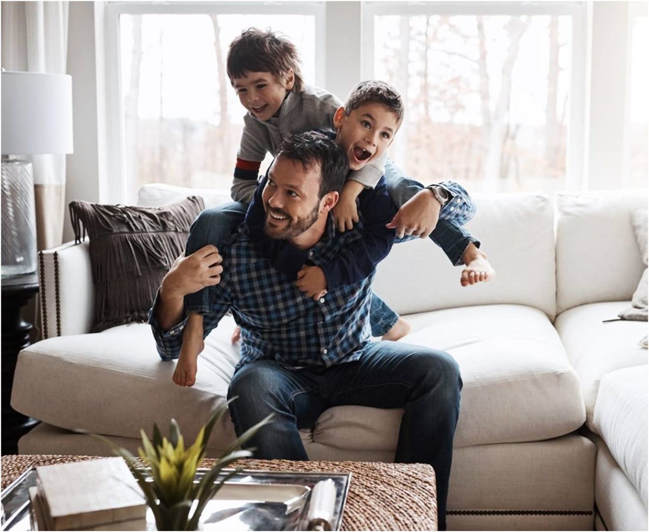 An image of a and and two boys on a sofa having fun