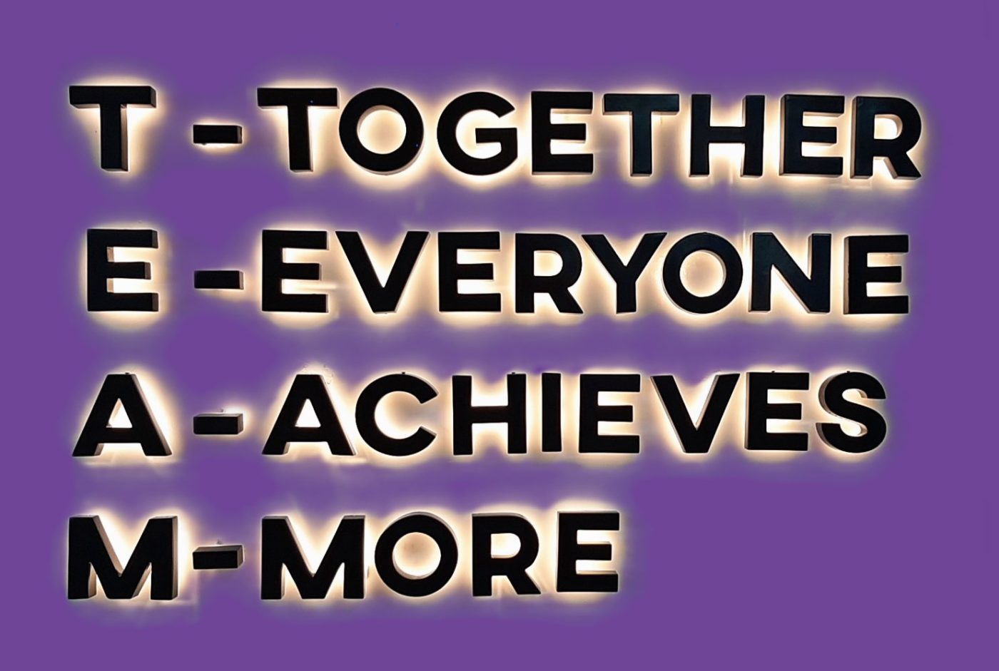 An image showing an illuminated mnemonic for TEAM on a liolac background - Together Everyone Achieves More