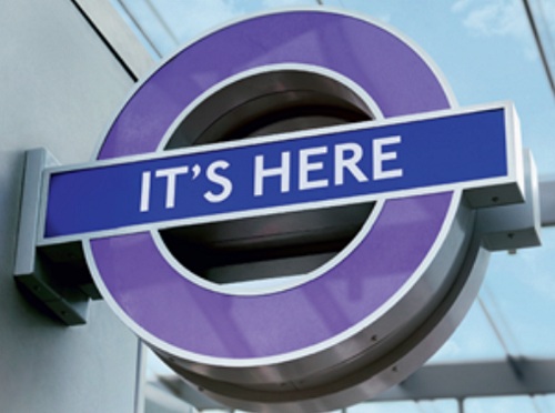 A purple version of the London Underground logo with the words "It's here" across the centre.