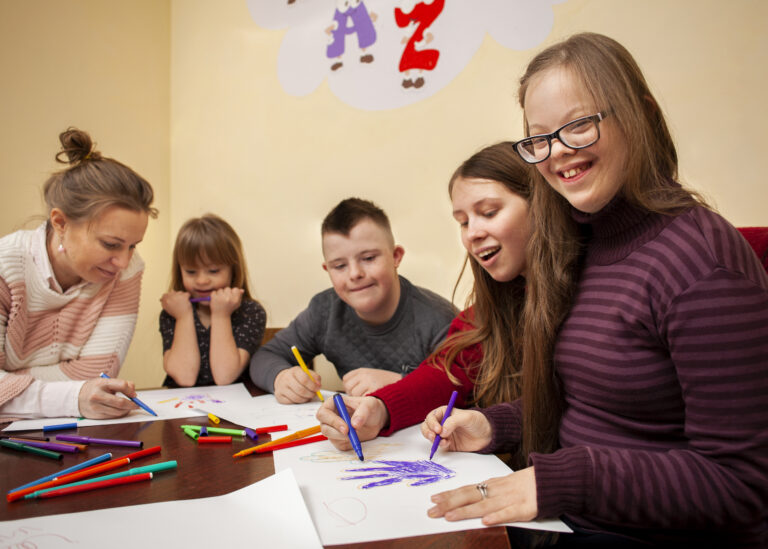 A placeholder image showing a diverse group of neurodiverse children and a teacher or parent happily drawing and learning together at a table, highlighting inclusive and accessible education. Designed by FREEPIK