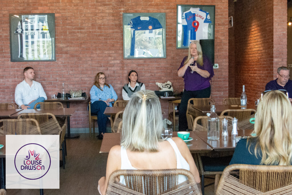 Louise Dawson (in purple shirt, holding microphone) presenting to a group of parents at the Just The Mums event.
