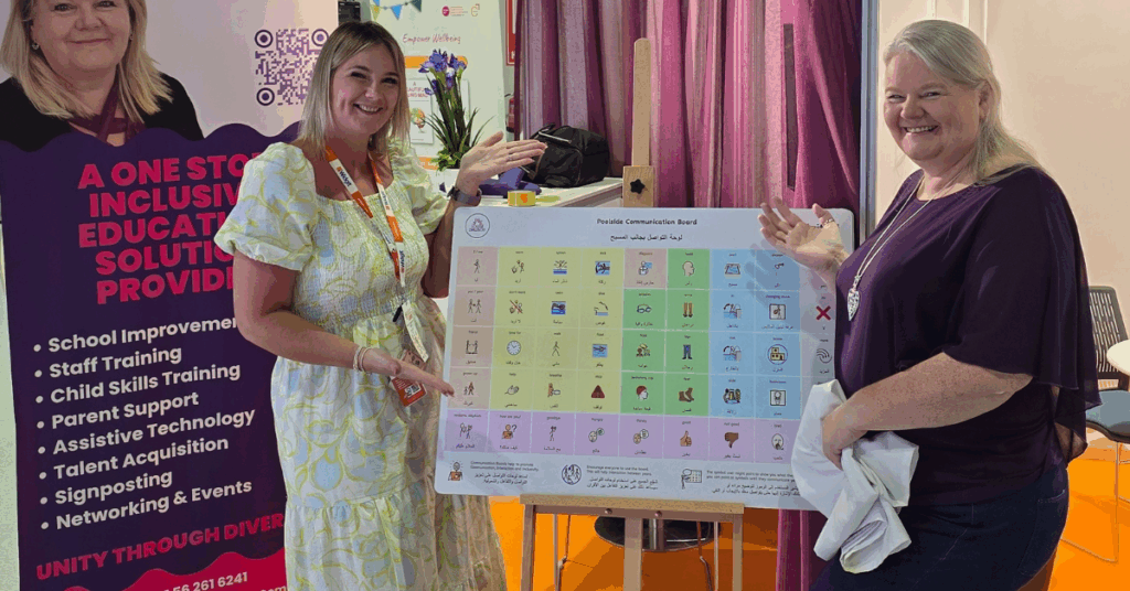 Louise Dawson Inclusion and Becca from Widgit showcasing a large Widgit Communication Board at their stand, pointing to the pictograms, demonstrating tools for inclusive communication.