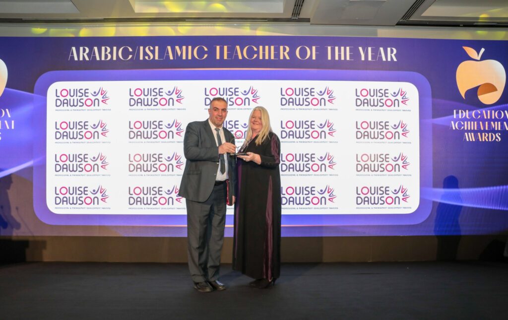 Louise Dawson presenting the Arabic/Islamic Teacher of the Year award to the male recipient on the Education Achievement Awards stage.