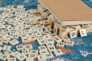 A box with jumbled wooden letter tiles spilling out of it representing difficulty with words and letters.
